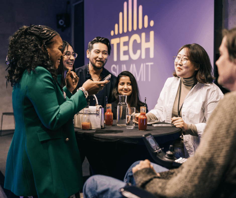 Group of people gathered around a table with drinks, engaged in conversation at a tech summit event.